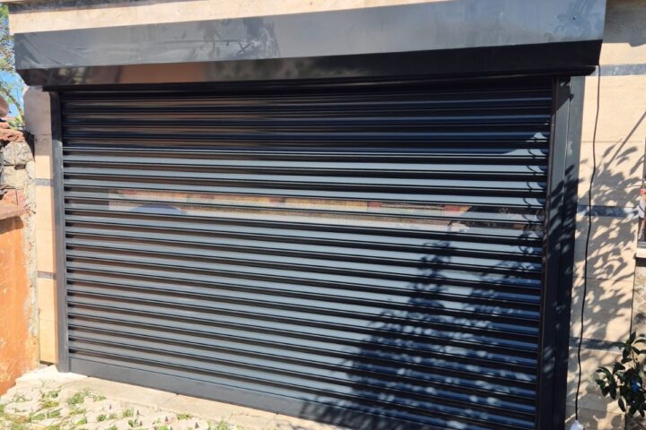 Müstakil bir binanın garaj girişine monte edilmiş, havalandırma bantlı koyu renk galvaniz çelik kepenk