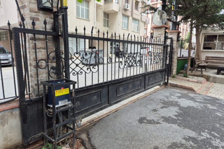 Siyah ferforje yana kayar bahçe kapısı ve yanındaki kumanda kutulu motor ünitesi